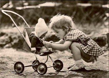 Bild: Kind spielt mit einer Puppe im Puppenwagen