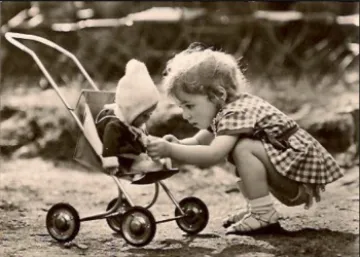 Bild: ein Kind kniet vor einem Puppenwagen und spielt
